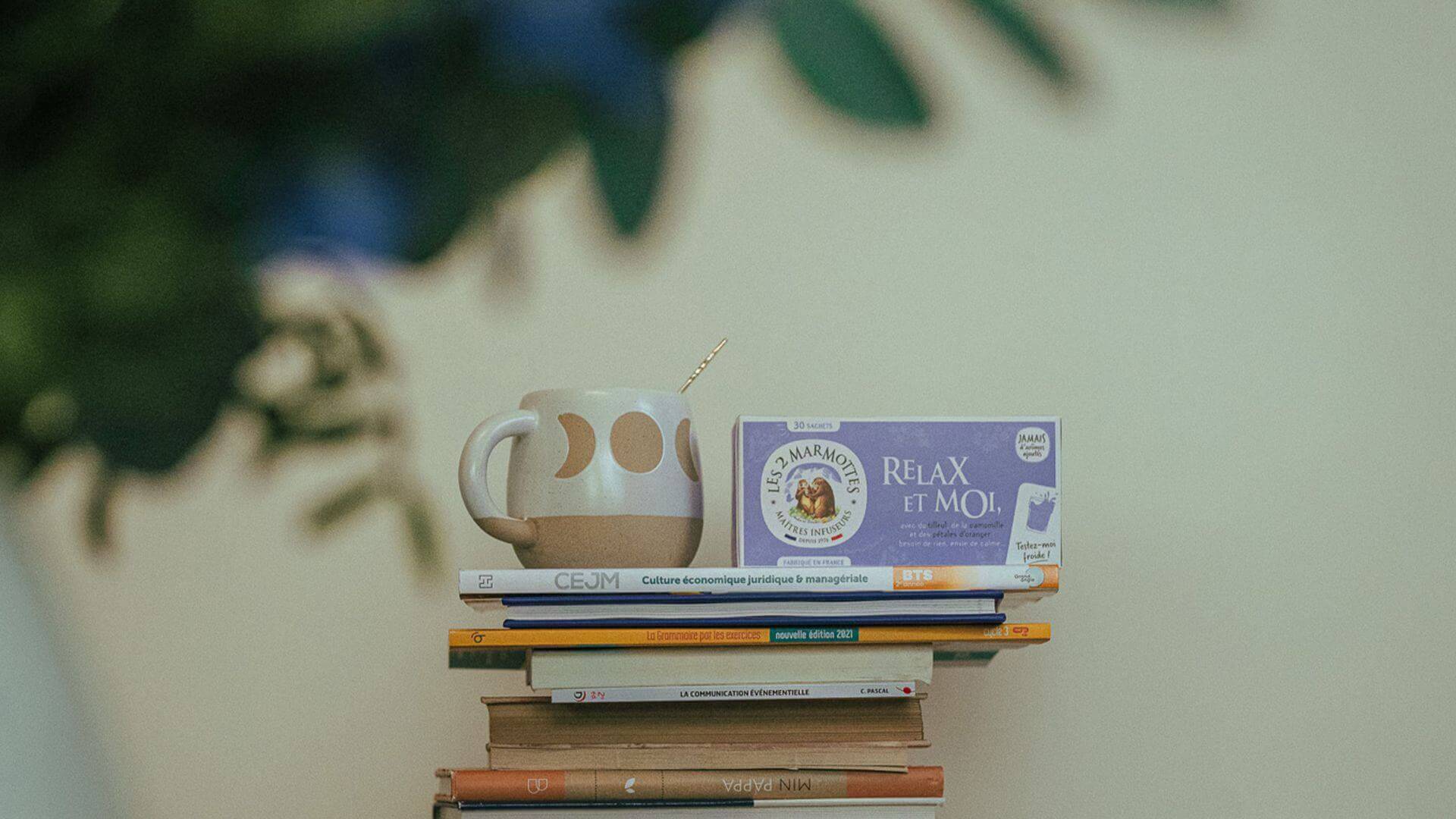 Boite de Relax&Moi posée sur une pile de livre avec tasse